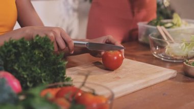 Kadın, sağlıklı yemek hazırlamak için mutfak tezgahında sebze kesiyor.