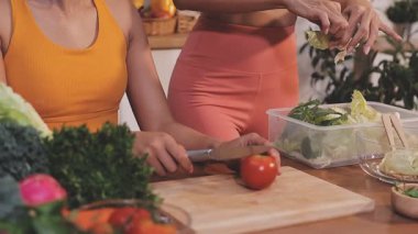 Kadın, sağlıklı yemek hazırlamak için mutfak tezgahında sebze kesiyor.
