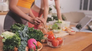 Kadın, sağlıklı yemek hazırlamak için mutfak tezgahında sebze kesiyor.