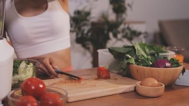 Kadın, sağlıklı yemek hazırlamak için mutfak tezgahında sebze kesiyor.