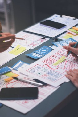 Uxui tasarımcılarından oluşan bir ekip bilgisayar ekranını işaret ederek ofiste yeni mobil uygulama tasarımını tartışıyor.