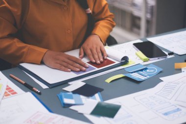 Uxui tasarımcılarından oluşan bir ekip bilgisayar ekranını işaret ederek ofiste yeni mobil uygulama tasarımını tartışıyor.