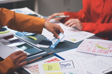 Uxui tasarımcılarından oluşan bir ekip bilgisayar ekranını işaret ederek ofiste yeni mobil uygulama tasarımını tartışıyor.