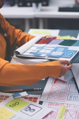 Uxui tasarımcılarından oluşan bir ekip bilgisayar ekranını işaret ederek ofiste yeni mobil uygulama tasarımını tartışıyor.