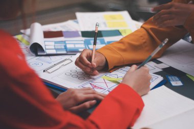 Uxui tasarımcılarından oluşan bir ekip bilgisayar ekranını işaret ederek ofiste yeni mobil uygulama tasarımını tartışıyor.