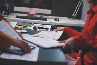 Uxui tasarımcılarından oluşan bir ekip bilgisayar ekranını işaret ederek ofiste yeni mobil uygulama tasarımını tartışıyor.