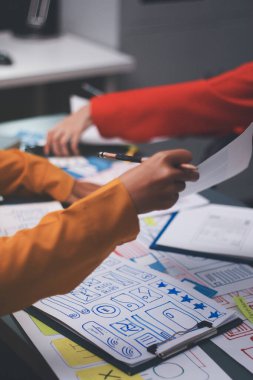 Uxui tasarımcılarından oluşan bir ekip bilgisayar ekranını işaret ederek ofiste yeni mobil uygulama tasarımını tartışıyor.