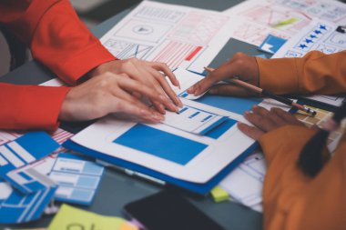 Uxui tasarımcılarından oluşan bir ekip bilgisayar ekranını işaret ederek ofiste yeni mobil uygulama tasarımını tartışıyor.