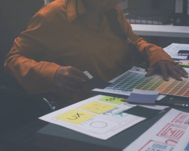 Uxui tasarımcılarından oluşan bir ekip bilgisayar ekranını işaret ederek ofiste yeni mobil uygulama tasarımını tartışıyor.