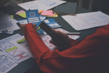 Uxui tasarımcılarından oluşan bir ekip bilgisayar ekranını işaret ederek ofiste yeni mobil uygulama tasarımını tartışıyor.