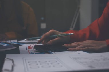 Uxui tasarımcılarından oluşan bir ekip bilgisayar ekranını işaret ederek ofiste yeni mobil uygulama tasarımını tartışıyor.