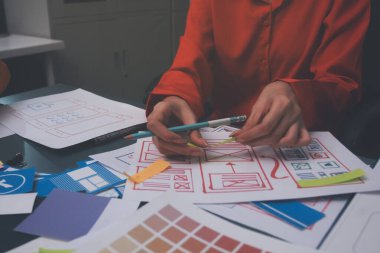 Uxui tasarımcılarından oluşan bir ekip bilgisayar ekranını işaret ederek ofiste yeni mobil uygulama tasarımını tartışıyor.