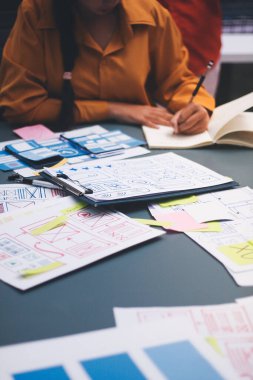 Uxui tasarımcılarından oluşan bir ekip bilgisayar ekranını işaret ederek ofiste yeni mobil uygulama tasarımını tartışıyor.