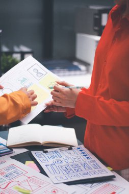 Uxui tasarımcılarından oluşan bir ekip bilgisayar ekranını işaret ederek ofiste yeni mobil uygulama tasarımını tartışıyor.