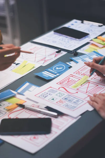 Uxui tasarımcılarından oluşan bir ekip bilgisayar ekranını işaret ederek ofiste yeni mobil uygulama tasarımını tartışıyor.