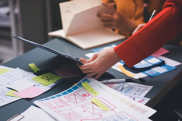 Uxui tasarımcılarından oluşan bir ekip bilgisayar ekranını işaret ederek ofiste yeni mobil uygulama tasarımını tartışıyor.