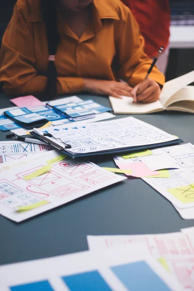 Uxui tasarımcılarından oluşan bir ekip bilgisayar ekranını işaret ederek ofiste yeni mobil uygulama tasarımını tartışıyor.