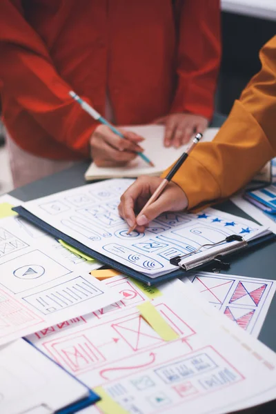 Uxui tasarımcılarından oluşan bir ekip bilgisayar ekranını işaret ederek ofiste yeni mobil uygulama tasarımını tartışıyor.