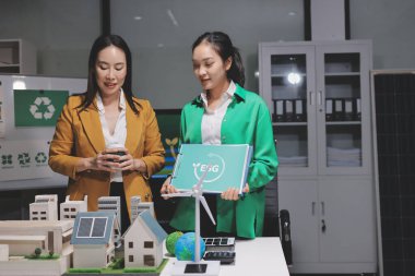 İki iş adamı ekibi güneş pili ve rüzgar türbini jeneratörü ile sürdürülebilir ve yenilenebilir temiz enerji ürünü, CO2 emisyonları küresel ısınma projesini planlıyor ve tartışıyor.