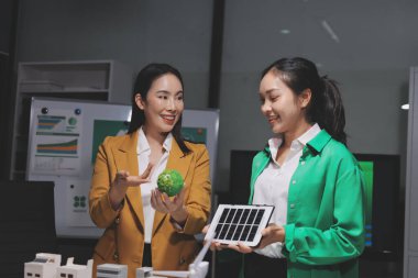 İki iş adamı ekibi güneş pili ve rüzgar türbini jeneratörü ile sürdürülebilir ve yenilenebilir temiz enerji ürünü, CO2 emisyonları küresel ısınma projesini planlıyor ve tartışıyor.