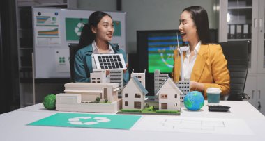 İki iş adamı ekibi güneş pili ve rüzgar türbini jeneratörü ile sürdürülebilir ve yenilenebilir temiz enerji ürünü, CO2 emisyonları küresel ısınma projesini planlıyor ve tartışıyor.