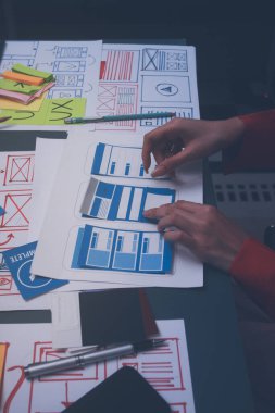 Uxui tasarımcılarından oluşan bir ekip bilgisayar ekranını işaret ederek ofiste yeni mobil uygulama tasarımını tartışıyor.