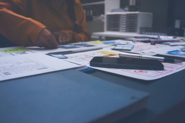 Uxui tasarımcılarından oluşan bir ekip bilgisayar ekranını işaret ederek ofiste yeni mobil uygulama tasarımını tartışıyor.