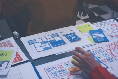 Uxui tasarımcılarından oluşan bir ekip bilgisayar ekranını işaret ederek ofiste yeni mobil uygulama tasarımını tartışıyor.