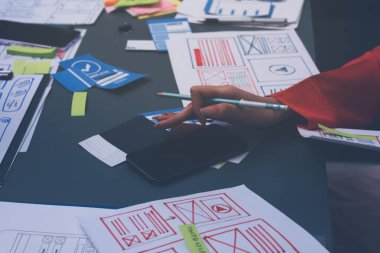 Uxui tasarımcılarından oluşan bir ekip bilgisayar ekranını işaret ederek ofiste yeni mobil uygulama tasarımını tartışıyor.