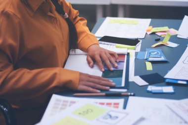 Uxui tasarımcılarından oluşan bir ekip bilgisayar ekranını işaret ederek ofiste yeni mobil uygulama tasarımını tartışıyor.