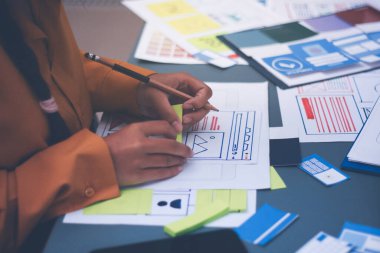 Uxui tasarımcılarından oluşan bir ekip bilgisayar ekranını işaret ederek ofiste yeni mobil uygulama tasarımını tartışıyor.