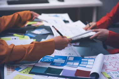 Uxui tasarımcılarından oluşan bir ekip bilgisayar ekranını işaret ederek ofiste yeni mobil uygulama tasarımını tartışıyor.