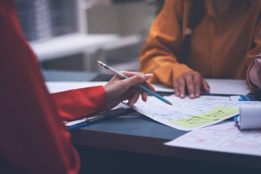 Uxui tasarımcılarından oluşan bir ekip bilgisayar ekranını işaret ederek ofiste yeni mobil uygulama tasarımını tartışıyor.