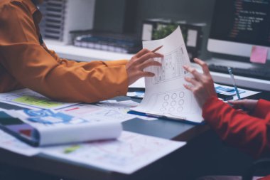 Uxui tasarımcılarından oluşan bir ekip bilgisayar ekranını işaret ederek ofiste yeni mobil uygulama tasarımını tartışıyor.