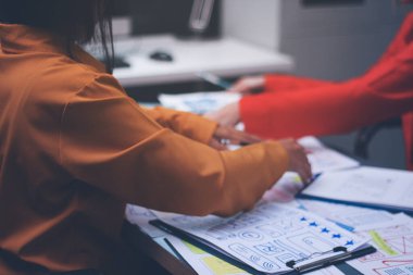 Uxui tasarımcılarından oluşan bir ekip bilgisayar ekranını işaret ederek ofiste yeni mobil uygulama tasarımını tartışıyor.