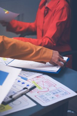 Uxui tasarımcılarından oluşan bir ekip bilgisayar ekranını işaret ederek ofiste yeni mobil uygulama tasarımını tartışıyor.