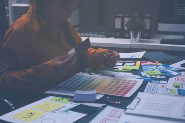 Uxui tasarımcılarından oluşan bir ekip bilgisayar ekranını işaret ederek ofiste yeni mobil uygulama tasarımını tartışıyor.