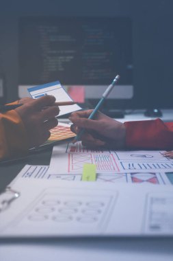 Uxui tasarımcılarından oluşan bir ekip bilgisayar ekranını işaret ederek ofiste yeni mobil uygulama tasarımını tartışıyor.