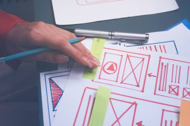 Uxui tasarımcılarından oluşan bir ekip bilgisayar ekranını işaret ederek ofiste yeni mobil uygulama tasarımını tartışıyor.