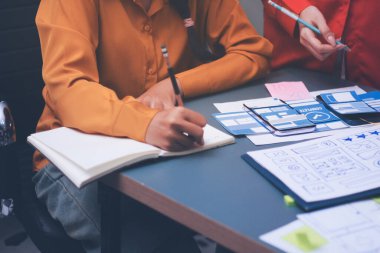 Uxui tasarımcılarından oluşan bir ekip bilgisayar ekranını işaret ederek ofiste yeni mobil uygulama tasarımını tartışıyor.