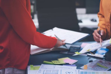 Uxui tasarımcılarından oluşan bir ekip bilgisayar ekranını işaret ederek ofiste yeni mobil uygulama tasarımını tartışıyor.