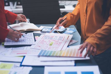 Uxui tasarımcılarından oluşan bir ekip bilgisayar ekranını işaret ederek ofiste yeni mobil uygulama tasarımını tartışıyor.