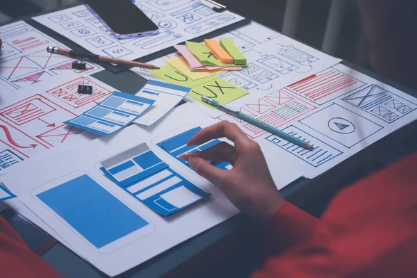 Uxui tasarımcılarından oluşan bir ekip bilgisayar ekranını işaret ederek ofiste yeni mobil uygulama tasarımını tartışıyor.