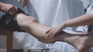 Doktor fizyoterapist yaralı dizini tedavi ediyor, sapını hastanın dizine dayayıp ağrısını kontrol ediyor..