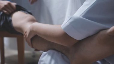 Doktor fizyoterapist yaralı dizini tedavi ediyor, sapını hastanın dizine dayayıp ağrısını kontrol ediyor..