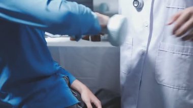 Evde fizyoterapistle egzersiz yapan mutlu yaşlı kadın. Emekli bir kadın rehabilitasyon seansı sırasında kişisel antrenörünün yardımıyla evde kollarını esnetiyor..