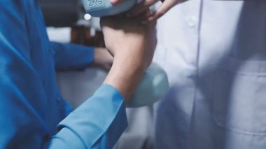 Evde fizyoterapistle egzersiz yapan mutlu yaşlı kadın. Emekli bir kadın rehabilitasyon seansı sırasında kişisel antrenörünün yardımıyla evde kollarını esnetiyor..