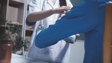 Evde fizyoterapistle egzersiz yapan mutlu yaşlı kadın. Emekli bir kadın rehabilitasyon seansı sırasında kişisel antrenörünün yardımıyla evde kollarını esnetiyor..