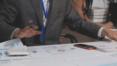 Ofis odasındaki hesap makinesinde finansal yatırım üzerinde çalışan iş adamları veya muhasebecilere yakından bakın..