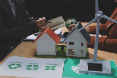 Ekip toplantısında, ESG konu sunumu için dizüstü bilgisayar kullanan Asyalı kadın, çok ırklı iş adamlarından oluşan genç bir gruba liderlik ediyor. Sürdürülebilir iş uygulaması, insanlar ev konseptinde çalışıyor